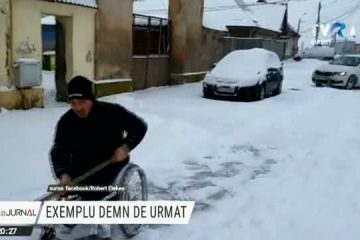Exemplu de urmat în Prejmer. Un bărbat în scaun cu rotile deszăpezește trotuarul și parcarea din fața casei